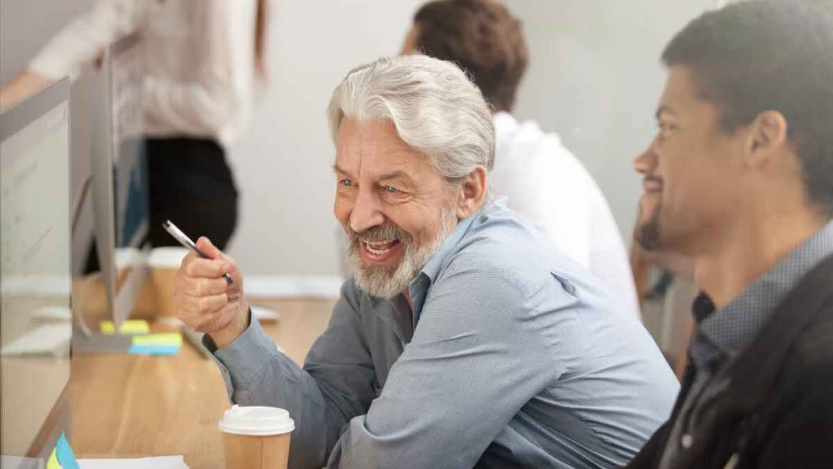 Hombre mayor sonriente en la oficina, símbolo de la generación 1960-1970 que logrará la jubilación al 100 % en 2025.