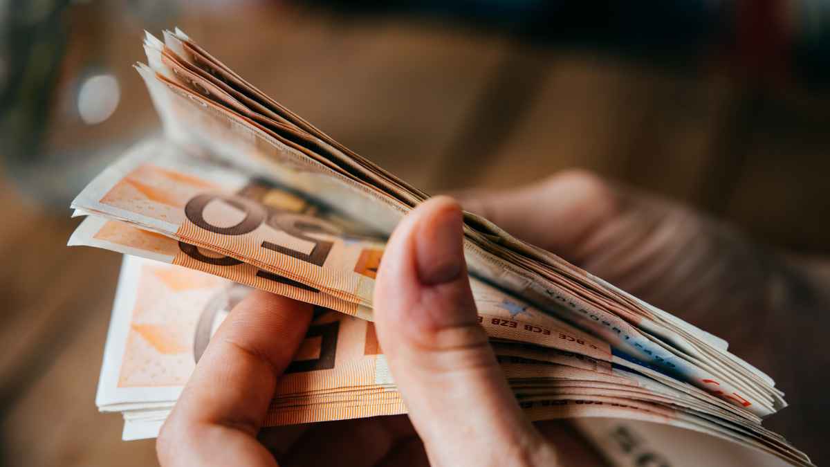 Manos contando billetes de 50 € que ilustran las ayudas económicas del Gobierno de España en 2025