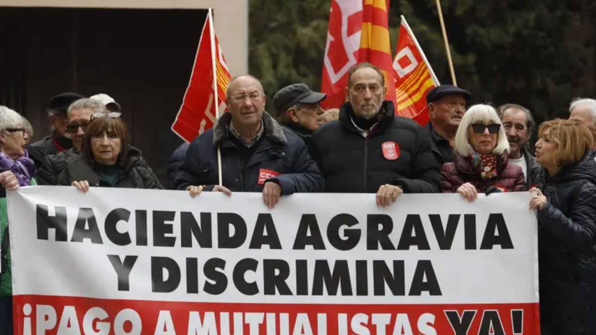Mutualistas protestando con pancarta “Hacienda agravia y discrimina” y banderas sindicales