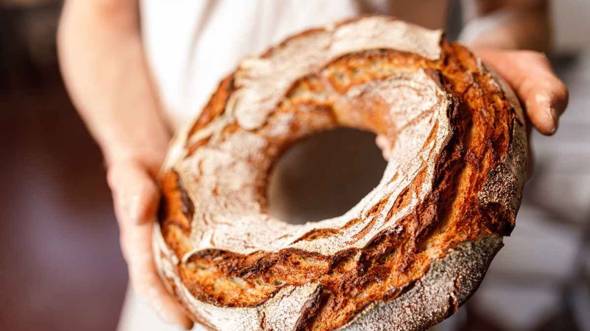 Domi Vélez, mejor panadero del mundo, sostiene pan artesanal en forma de rosca con corteza dorada y crujiente