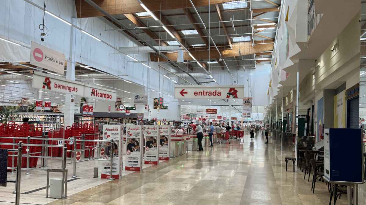 Interior supermercado Alcampo con carritos y señal de entrada en tienda afectada por cierre de 25 establecimientos