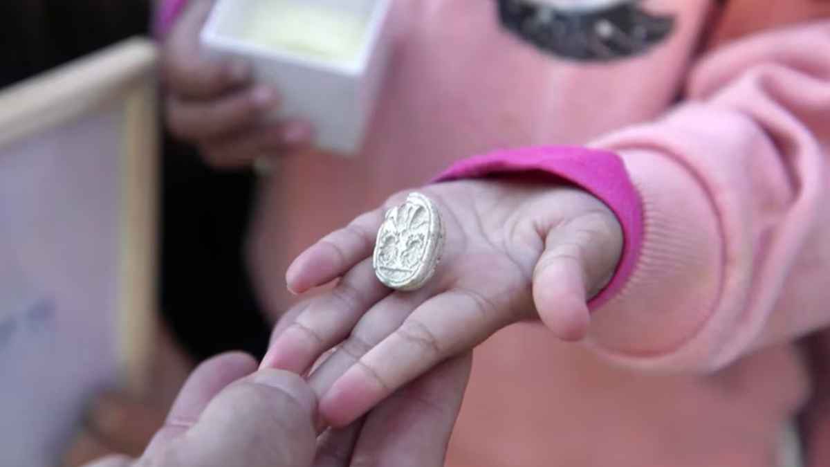 Mano de una niña mostrando un amuleto egipcio de la Edad del Bronce Medio hallado en Tel Azeka, Israel