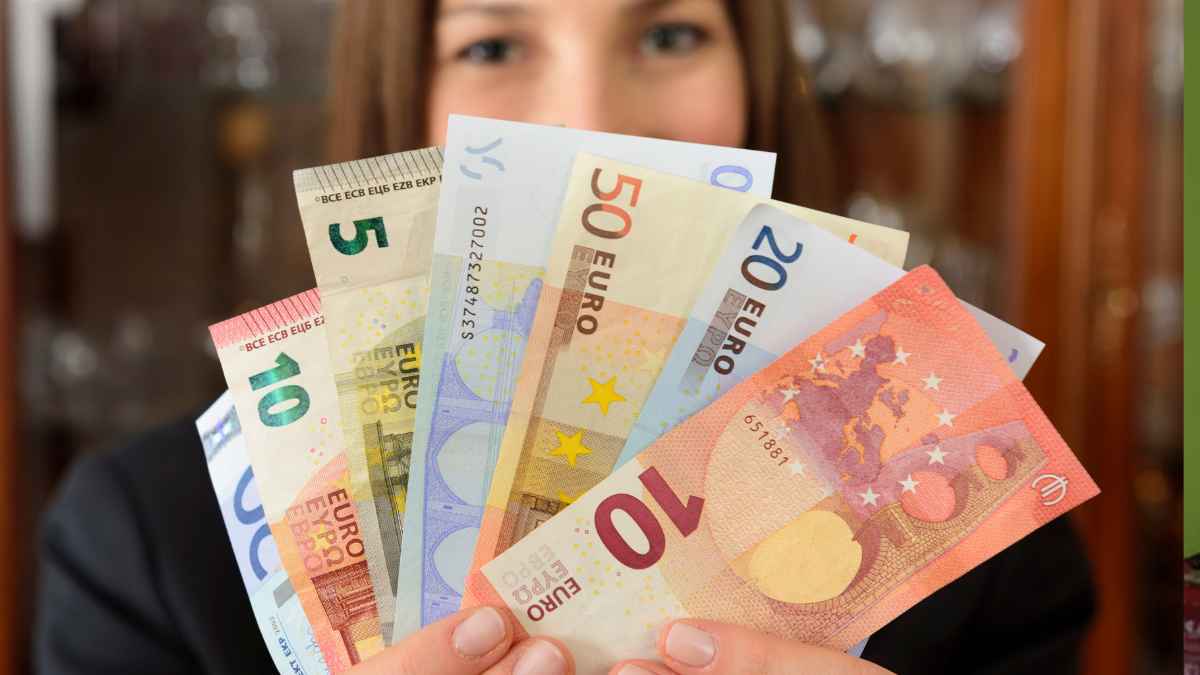 Mujer sosteniendo varios billetes de euro tras conseguir la paga del SEPE de 570 euros con solo 90 días cotizados