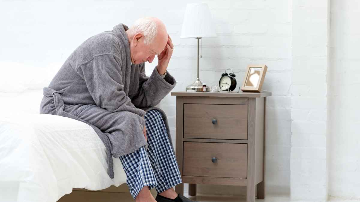 Jubilado preocupado sentado en la cama por la eliminación de la paguilla de las pensiones 2025
