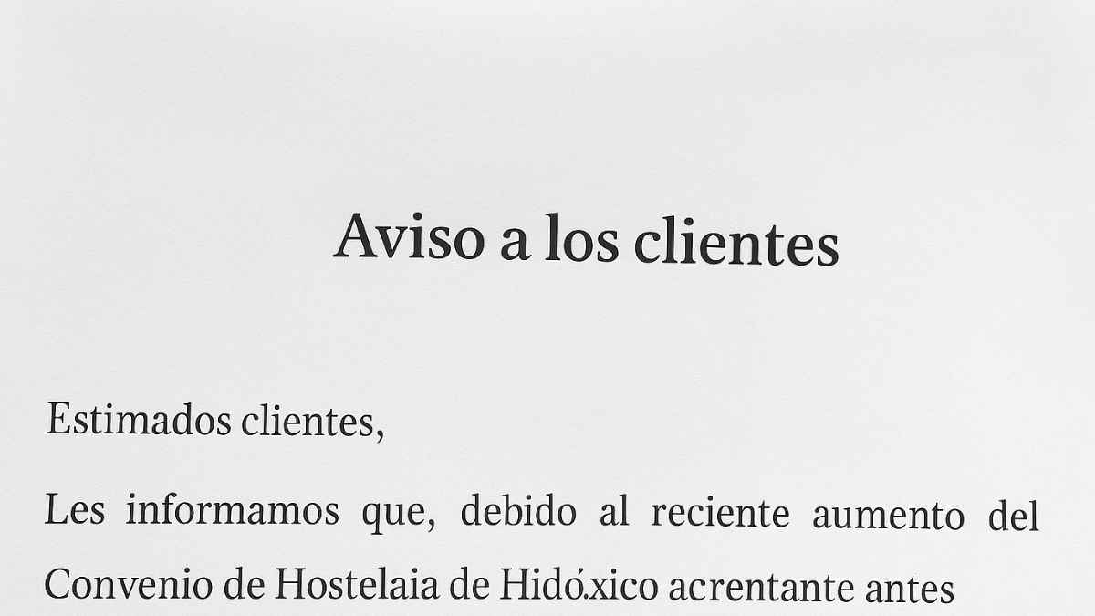 Cartel en la puerta de una pizzería de Bilbao anunciando un recargo de un euro extra por la subida de precios tras el convenio de hostelería.