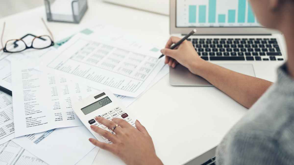 Mujer revisa su nómina con calculadora y portátil para comprobar grupo de cotización y antigüedad