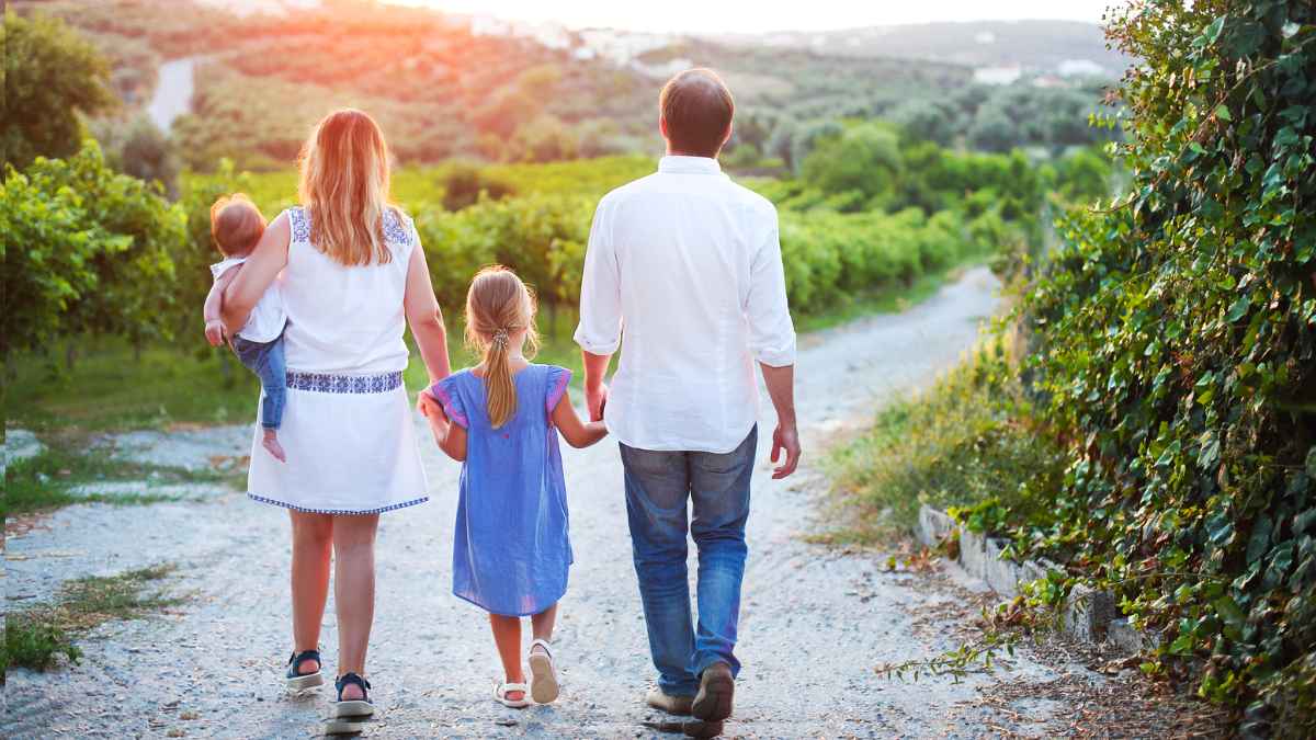 Padres con dos hijos pasean juntos, ejemplo de familias que pueden recibir la ayuda de 1.000 € de la Seguridad Social para menores de 17 años.