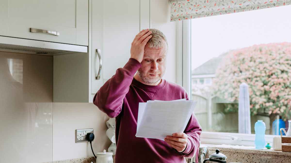 Hombre preocupado revisa notificación del sepe que avisa suspensión del subsidio para mayores de 52 años por no presentar la declaración anual de rentas dar