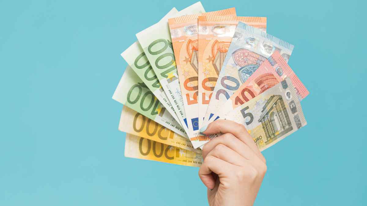 Mano sosteniendo varios billetes de euro que simbolizan el subsidio de 11.520 euros para mujeres en paro aprobado por el SEPE