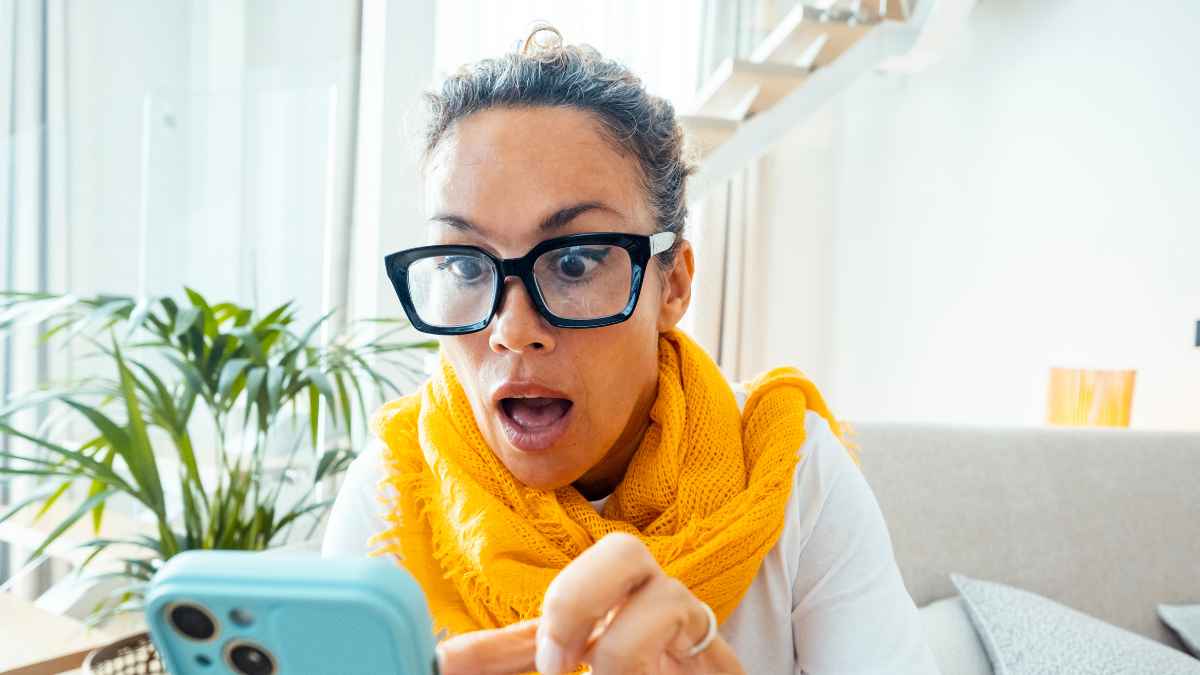 Mujer sorprendida mira su móvil ante posible fraude de SIM swapping que pone en riesgo su cuenta bancaria