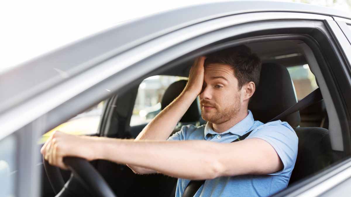 Conductor joven preocupado en su coche tras posible denegación de la DGT para renovar el carnet por medicamento sin informe médico