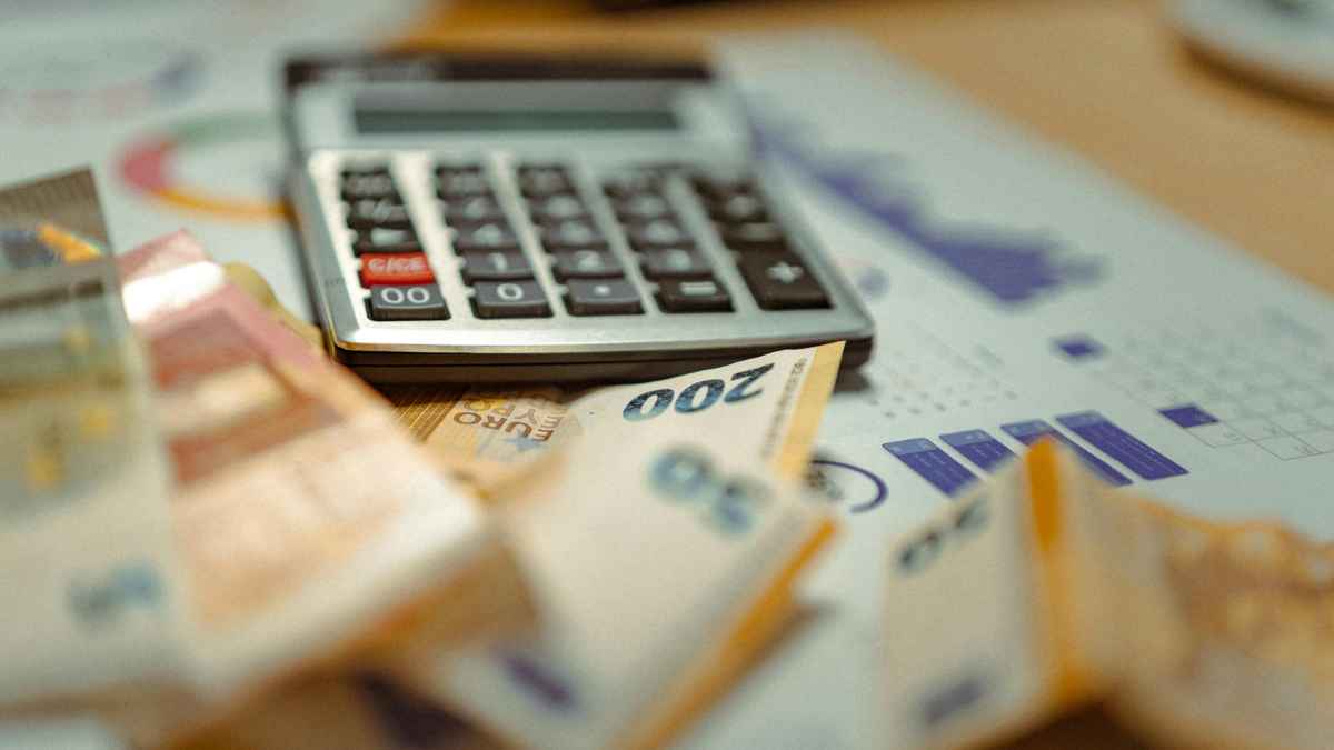 Calculadora y billetes de euro sobre gráficos para calcular finiquito, salario pendiente, vacaciones y pagas extras