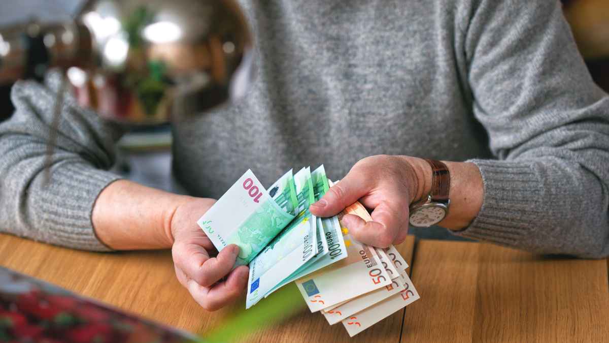Manos de persona mayor contando euros para subsidio mayores de 52 años