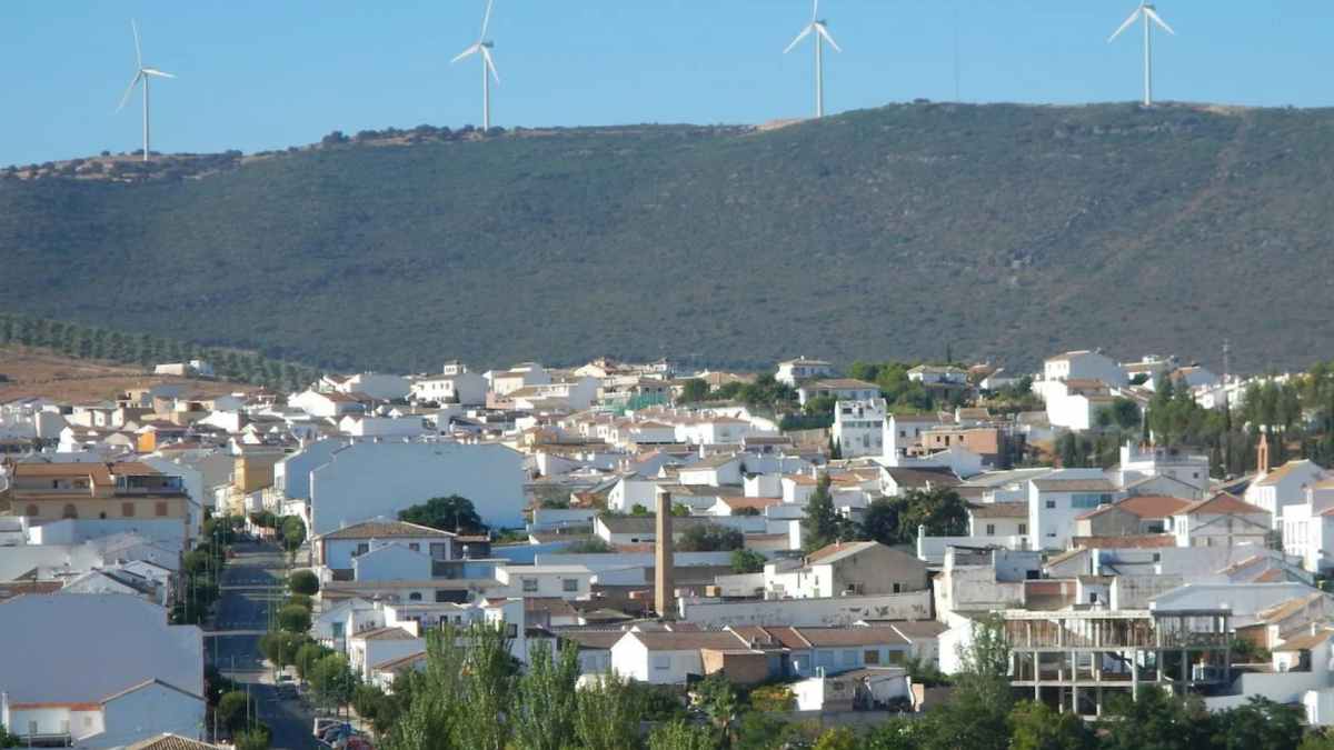 Vista panorámica de Villanueva de Algaidas, Málaga, con casas blancas asequibles y aerogeneradores en la sierra