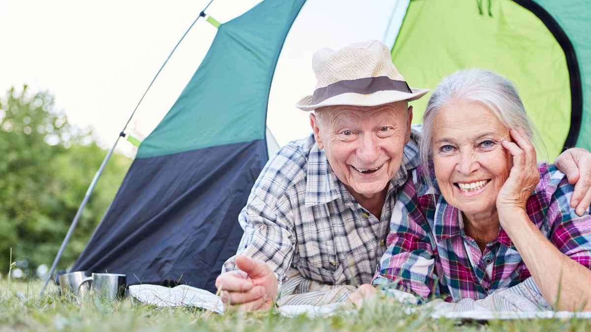 Pareja de pensionistas sonríe frente a una tienda de campaña gracias a los descuentos del Certificado Integral de Prestaciones