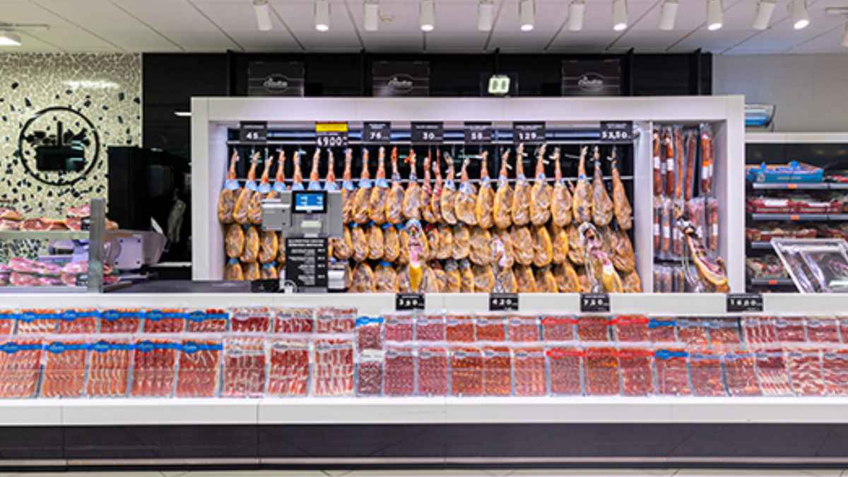Sección de charcutería con jamones colgados en un supermercado Mercadona