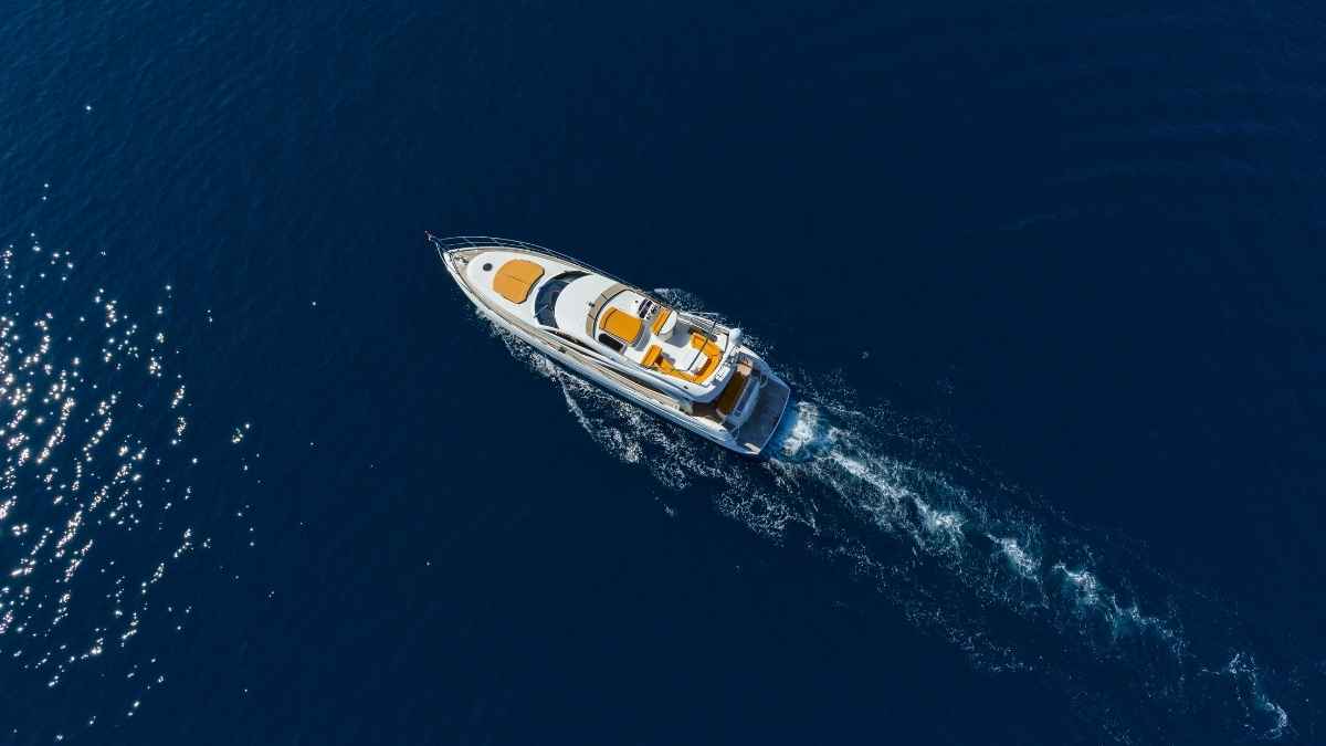 Yate de lujo visto desde el aire navegando a toda velocidad por aguas azules
