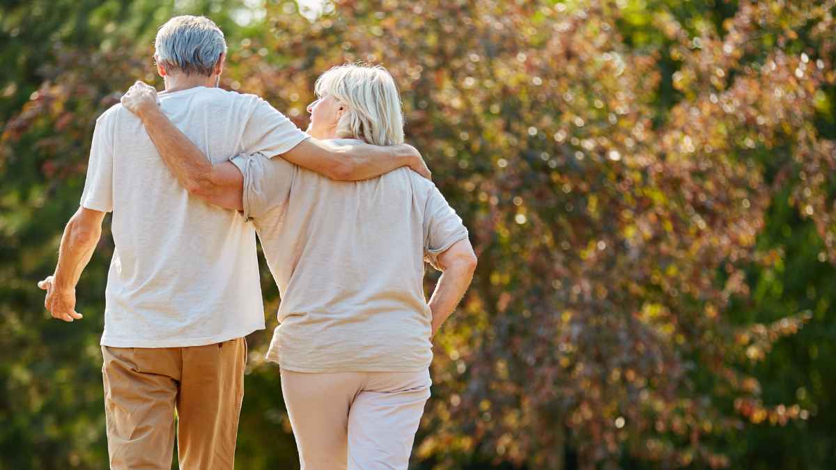 Pareja de jubilados caminando abrazados en un parque, símbolo de la edad de jubilación para nacidos entre 1960 y 1969