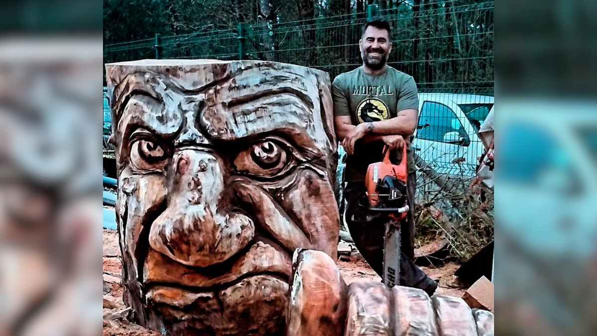 Escultor gallego con motosierra junto a gran escultura de madera tallada