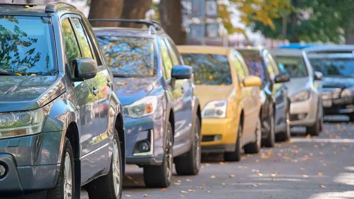 Coches aparcados en fila en una calle urbana; guardar sitio para aparcar puede acarrear multas de hasta 200 €