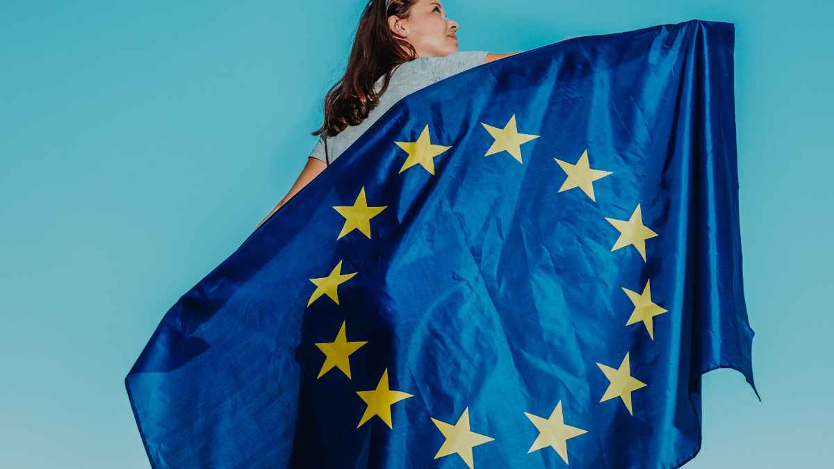 Mujer joven con bandera europea, inscripción Europa Joven para estudiar idiomas y prácticas pagadas