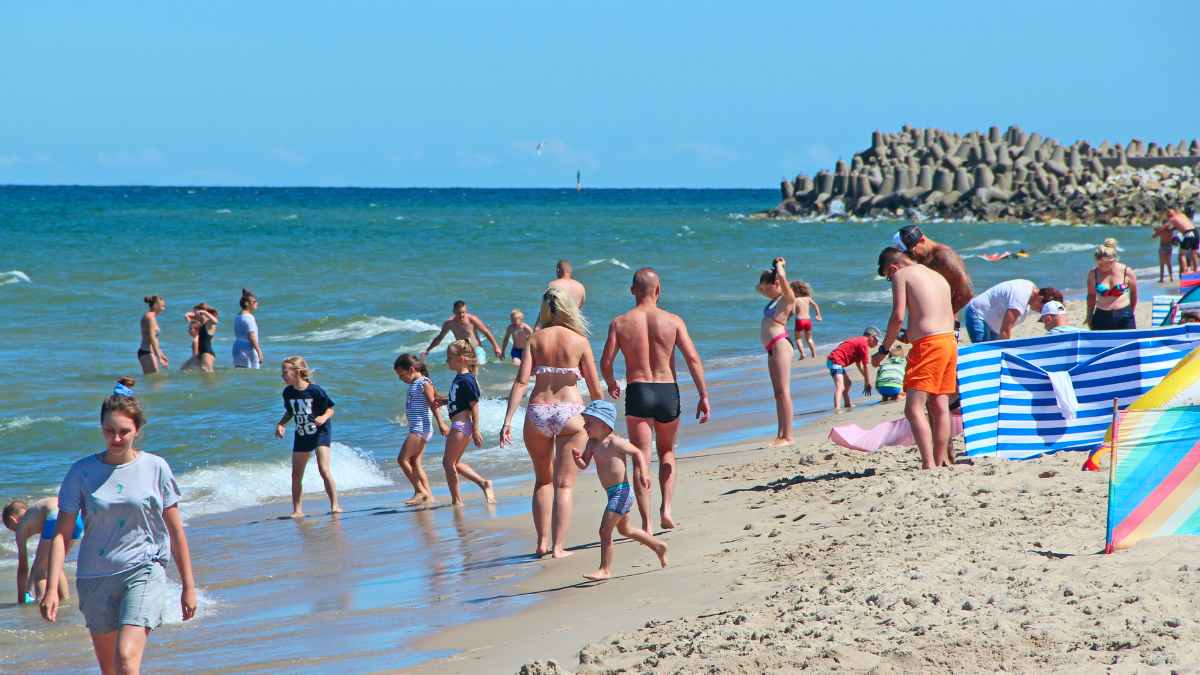 Familias disfrutando vacaciones en playa tras reducción jornada laboral