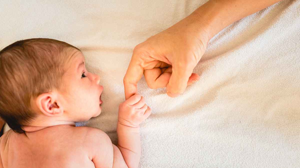 Bebé recién nacido agarra el dedo de su madre, símbolo de la cotización extra por parto y cuidado de hijos de la Seguridad Social