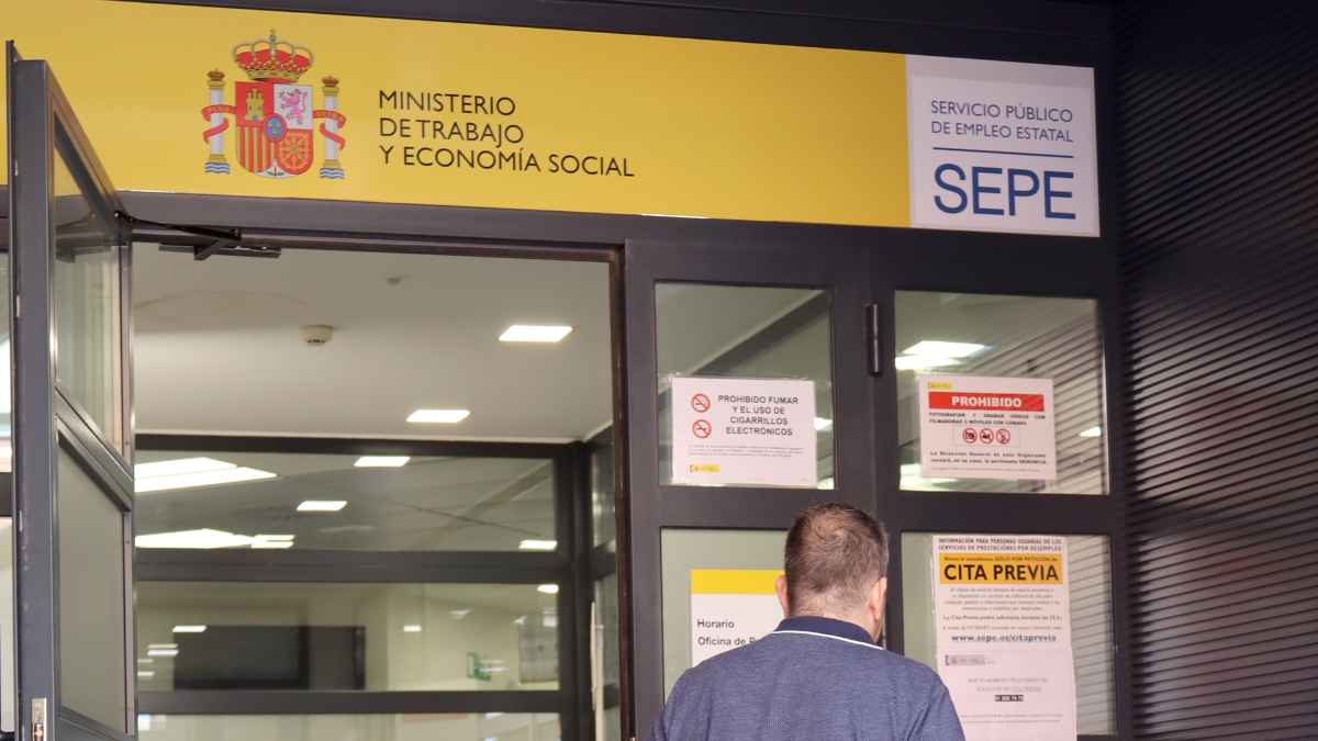 Entrada oficina SEPE Ministerio Trabajo con desempleado gestionando prestación compatible con empleo a jornada completa