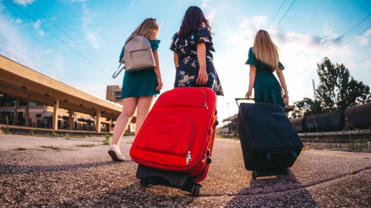 Tres chicas jóvenes con maletas en estación de tren usando descuento Verano Joven 2025 de Renfe