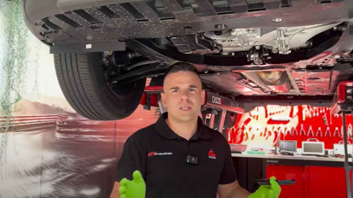 Mecánico revisando el motor averiado de un Volkswagen Golf en el taller, coche al borde del desguace