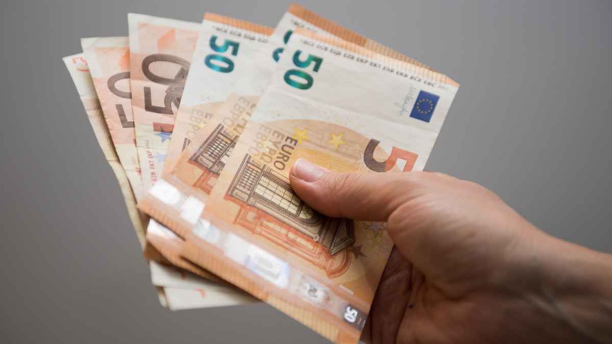 Mano sujetando billetes de euro representando ayudas económicas para mayores de 50 años