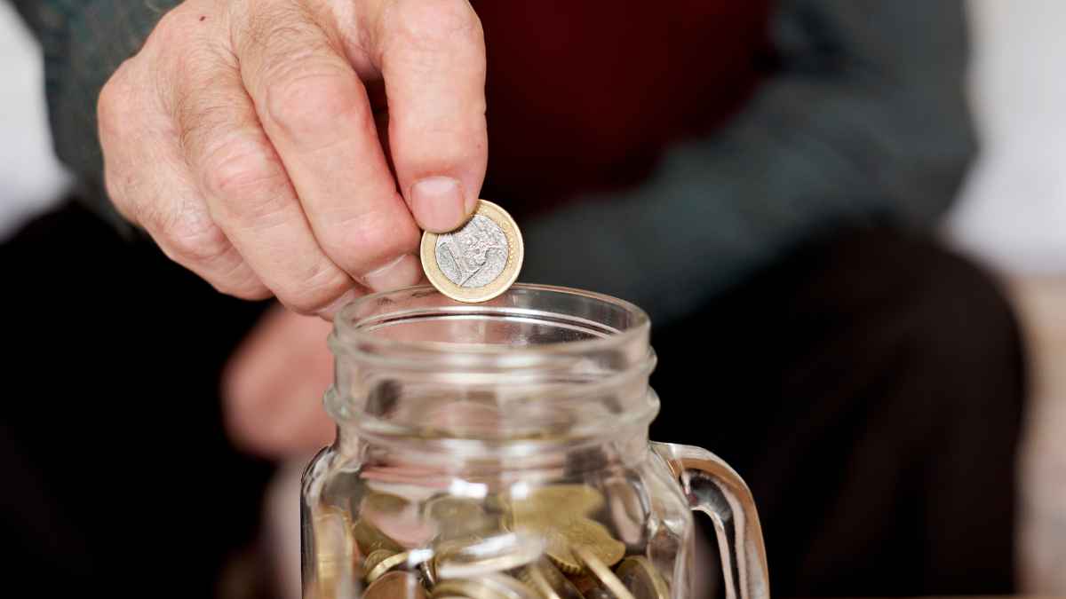 Anciano de 91 años colocando monedas en un jarrón como método de ahorro