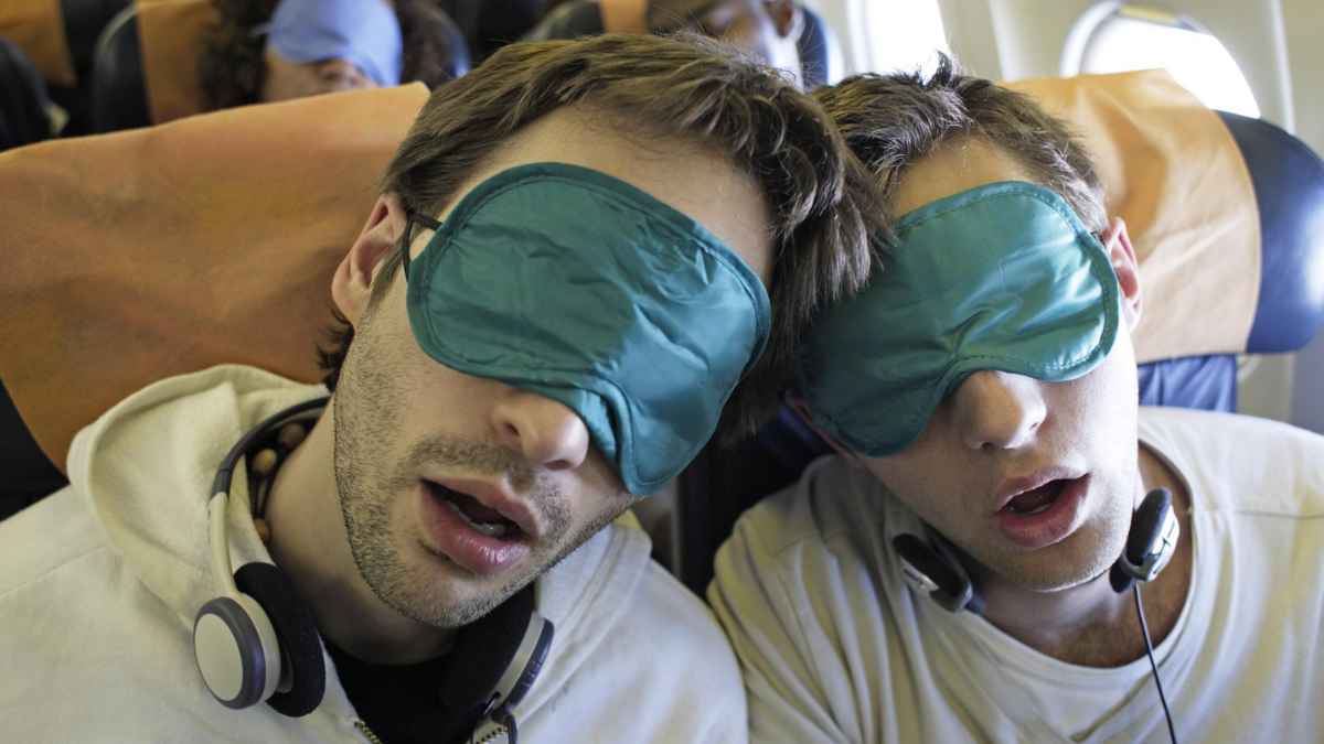 Dos pasajeros durmiendo con antifaz en vuelo largo