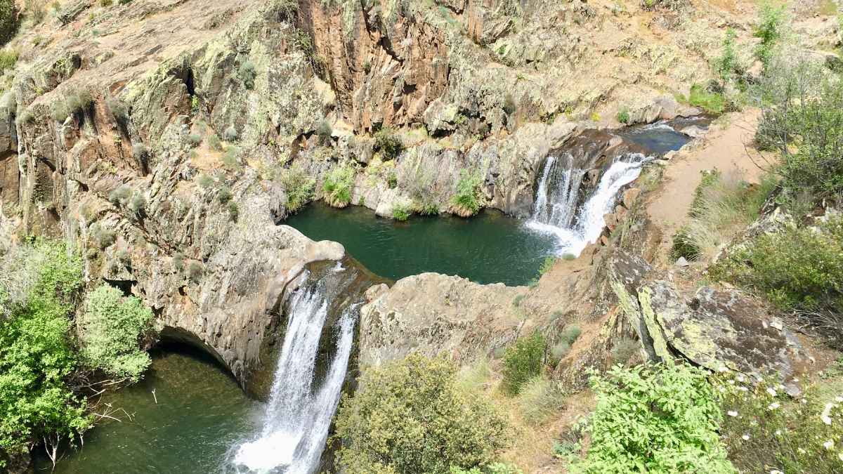 Vista aérea de las cascadas del Aljibe, dos saltos de agua encadenados entre acantilados de pizarra en Roblelacasa, Guadalajara.
