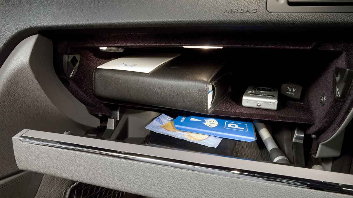 Interior guantera coche con objetos visibles, como documentos y tarjetas, que pueden ser un riesgo de robo según la Guardia Civil.