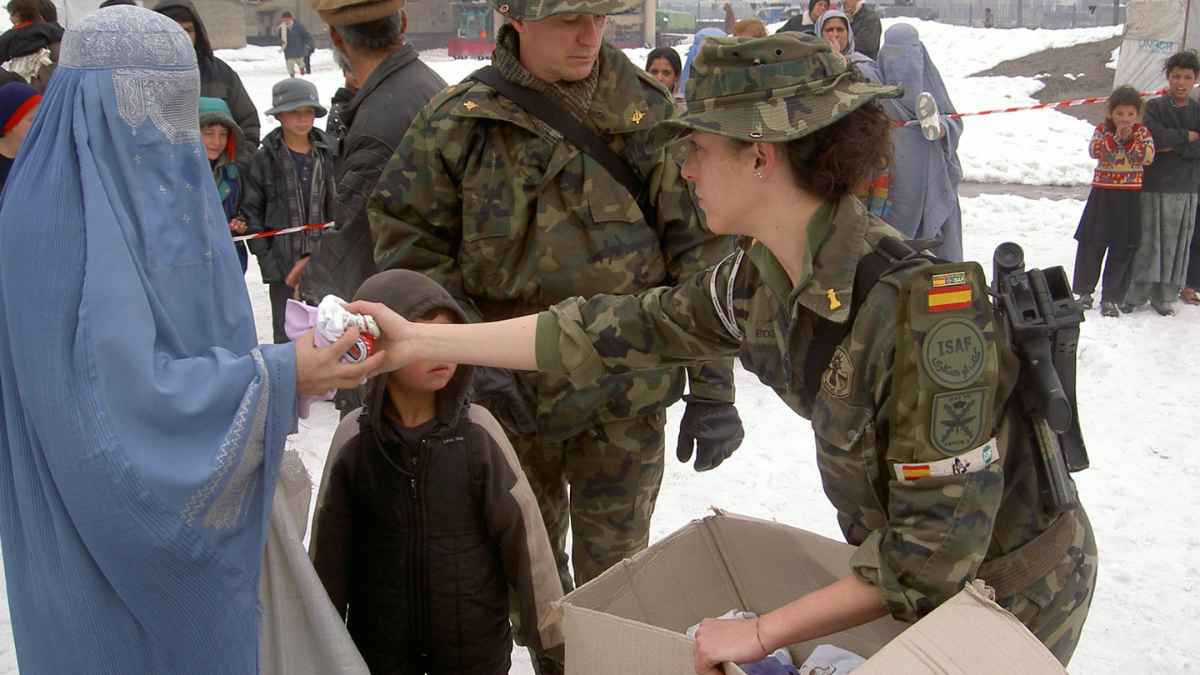 Soldados españoles en misión humanitaria repartiendo ayuda a civiles.