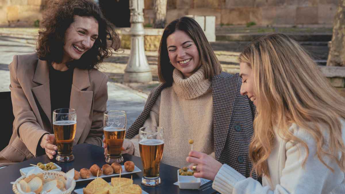 Tres amigas consumiendo bebidas y tapas en una terraza tras la prohibición de dividir la cuenta en bares y restaurantes