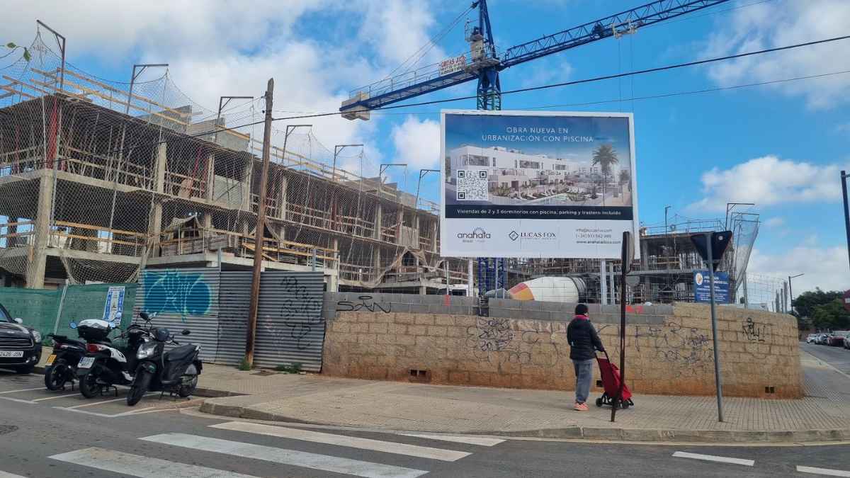 Construcción de nuevos pisos en Ibiza con cartel de obra nueva y detalles sobre viviendas con piscina y parking.