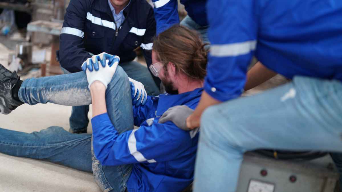 Trabajador herido siendo asistido por compañeros en un accidente laboral, lo que podría dar derecho a pensión por incapacidad permanente.