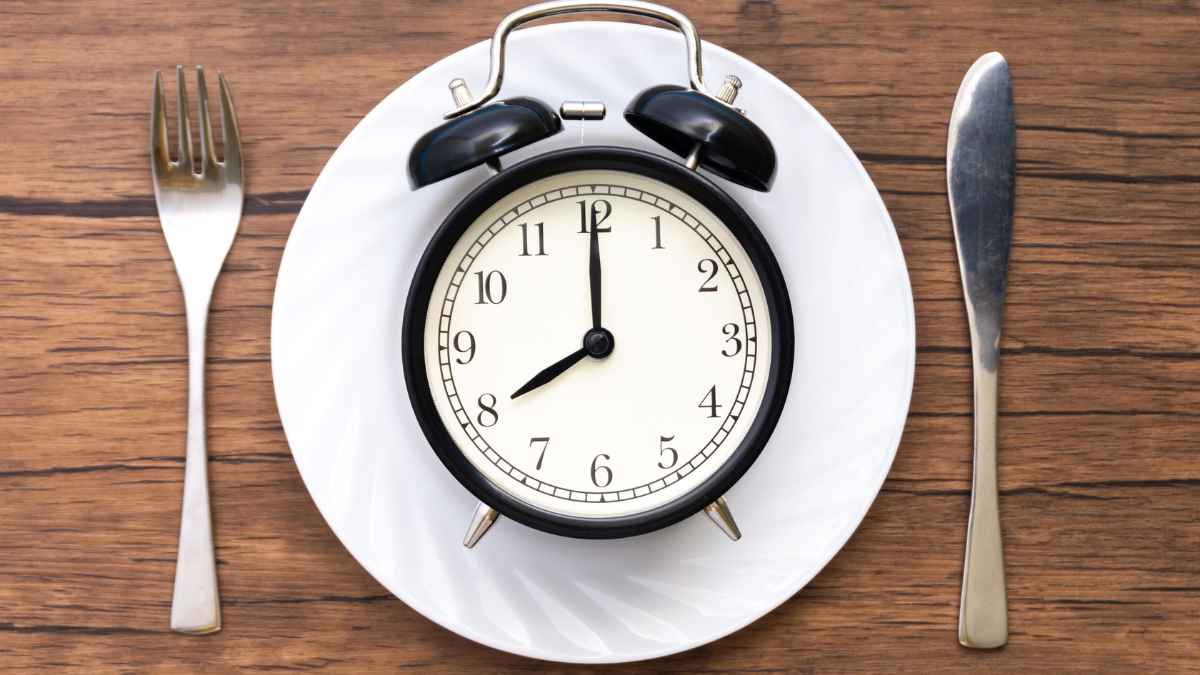 Reloj sobre plato indicando la mejor hora para cenar y dormir bien