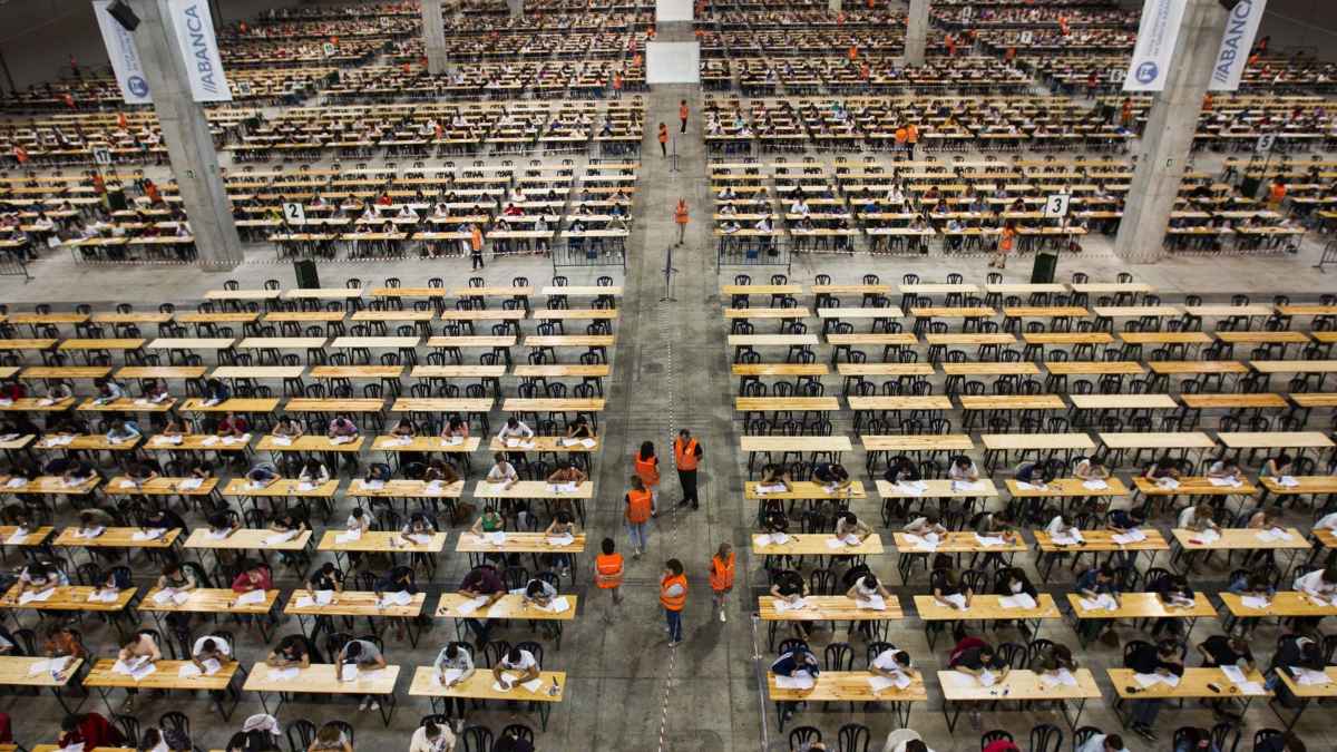 Aspirantes realizando un examen para la oferta de empleo público OEP 2025, con 36.588 plazas disponibles, en un gran espacio de examen.