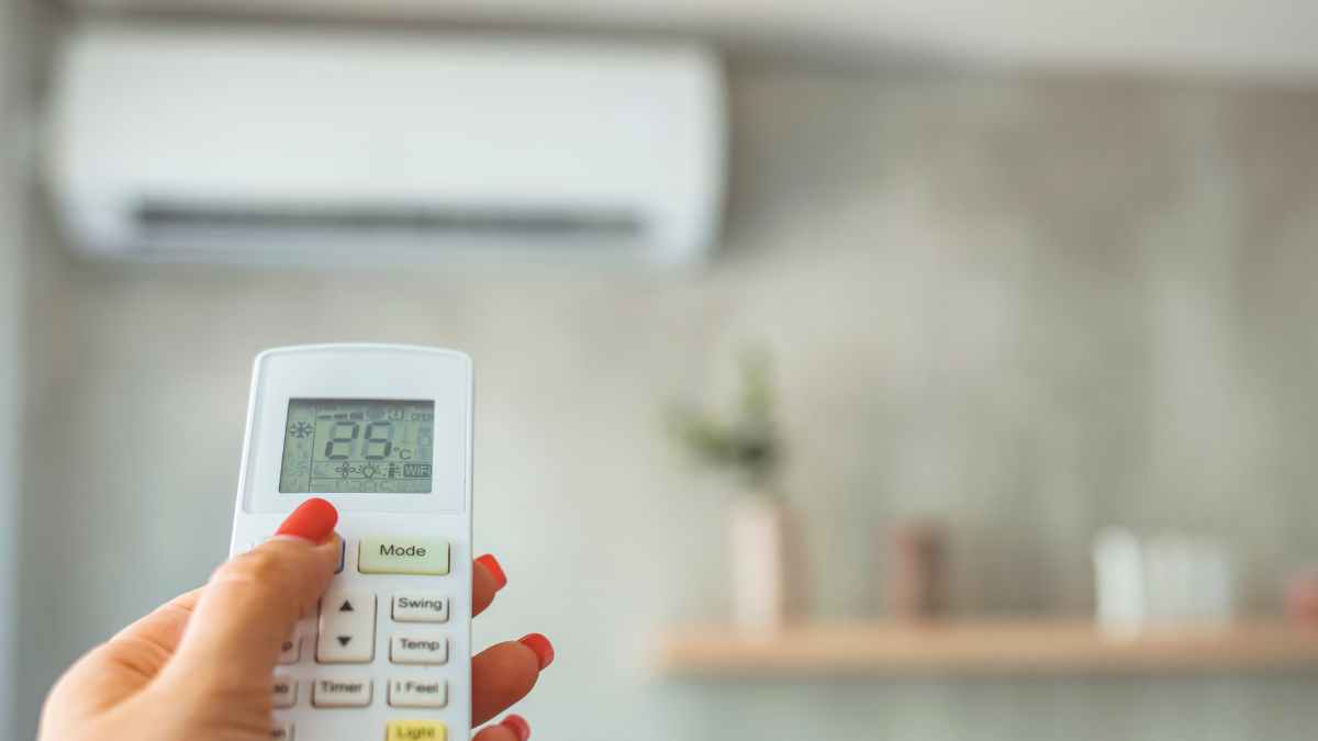 Mano ajustando temperatura del aire acondicionado para ahorrar en la factura de luz
