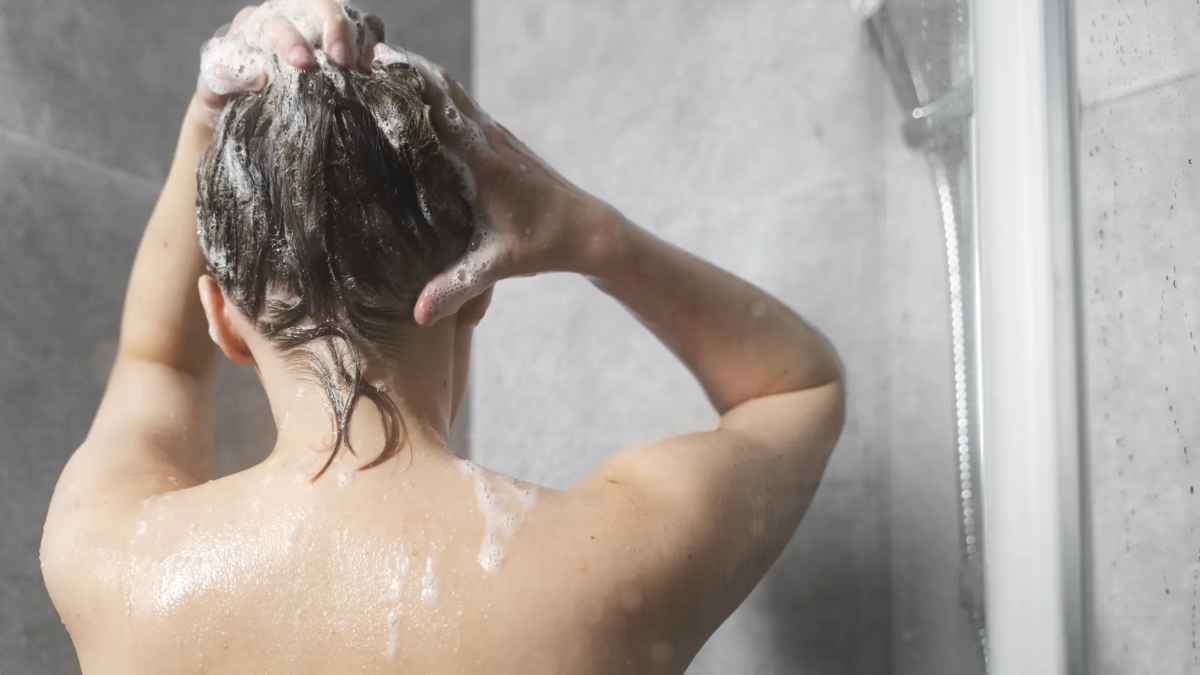 Mujer lavándose el cabello en la ducha con champú y sal para fortalecer y eliminar grasa