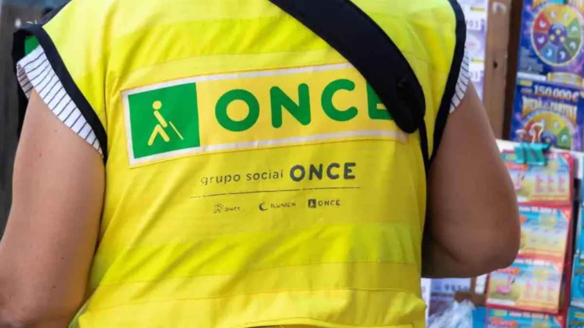Vendedor de lotería con chaleco amarillo de la ONCE trabajando en su puesto, afectado por enfermedad que lo obliga a ir al baño cada dos horas