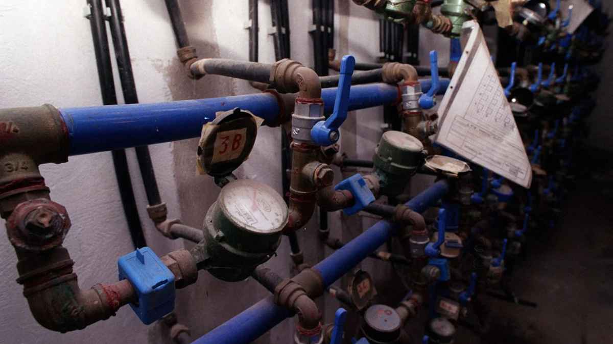 Contadores de agua antiguos y llaves de paso azules en una comunidad de vecinos pendientes de renovación antes de septiembre.