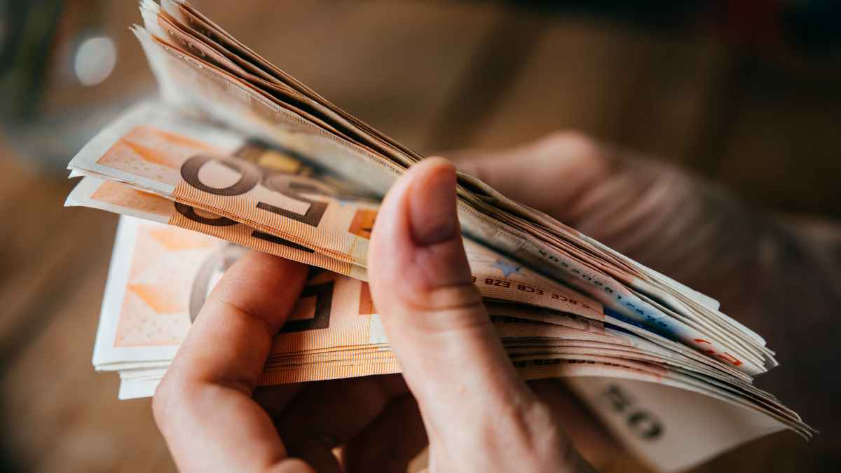 Mano contando billetes de 50 euros sobre ayuda del SEPE y subsidio por desempleo