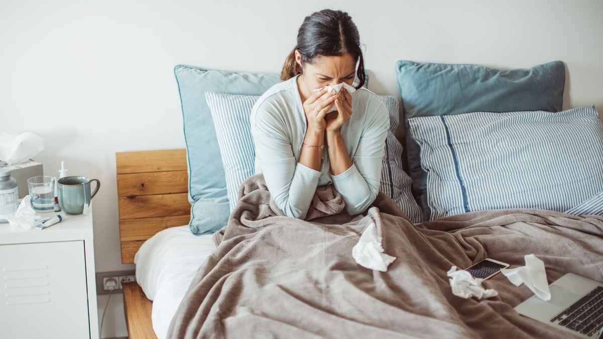Mujer enferma en cama con pañuelos por baja médica