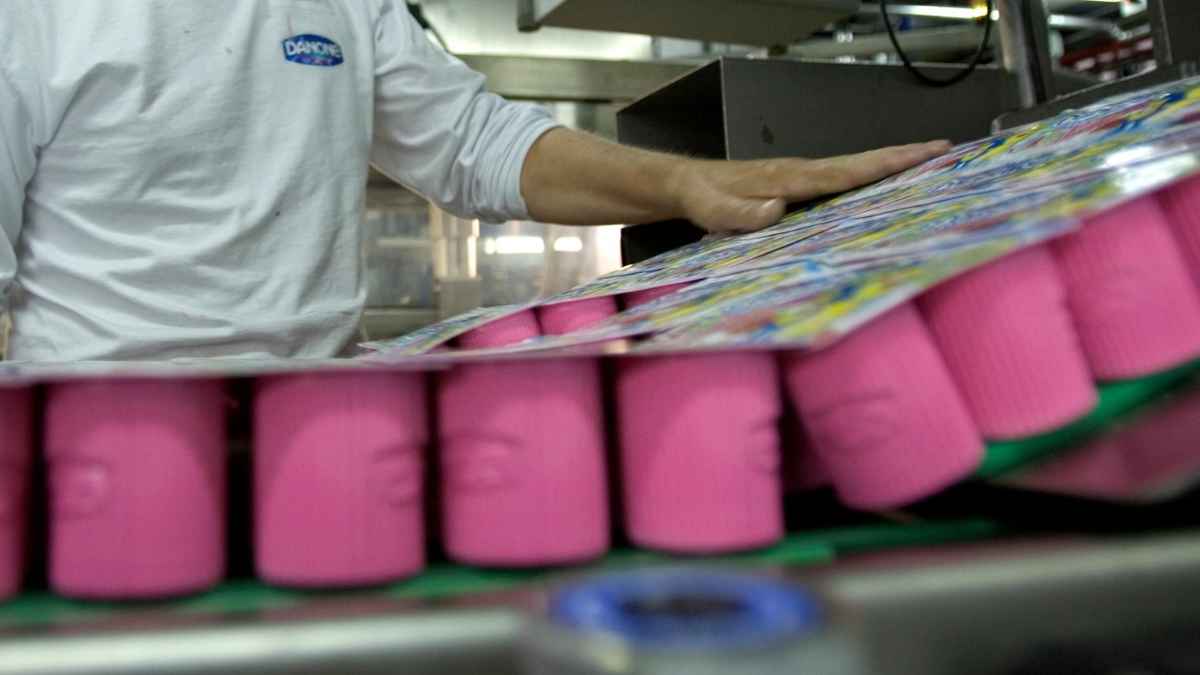 Operario de Danone revisando envases de yogur en fábrica; empresa lanza 29 ofertas de empleo indefinido sin experiencia
