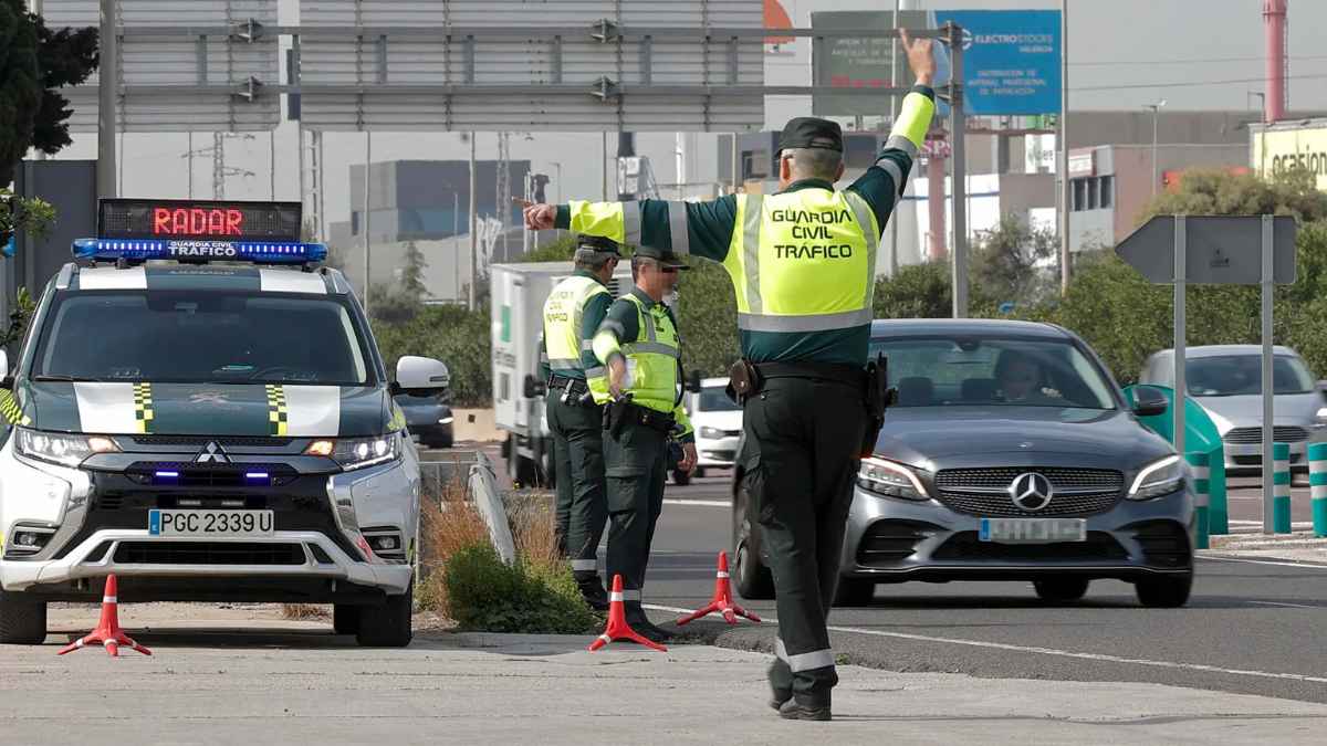 Agentes de la Guardia Civil de Tráfico revisan un radar fijo y dirigen vehículos durante un control en carretera.