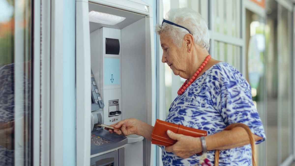 Mujer mayor sacando dinero de un cajero automático tras cobrar subsidio del IMSERSO